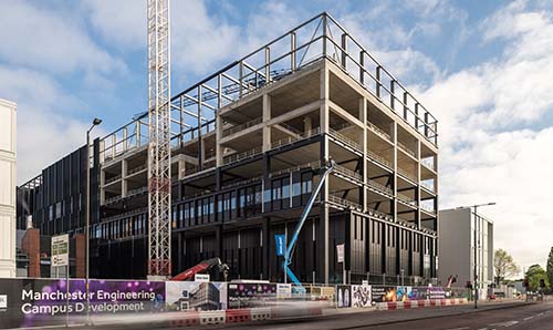 The building during the construction phase, showing the building as a steel frame with cranes also in the skyline.